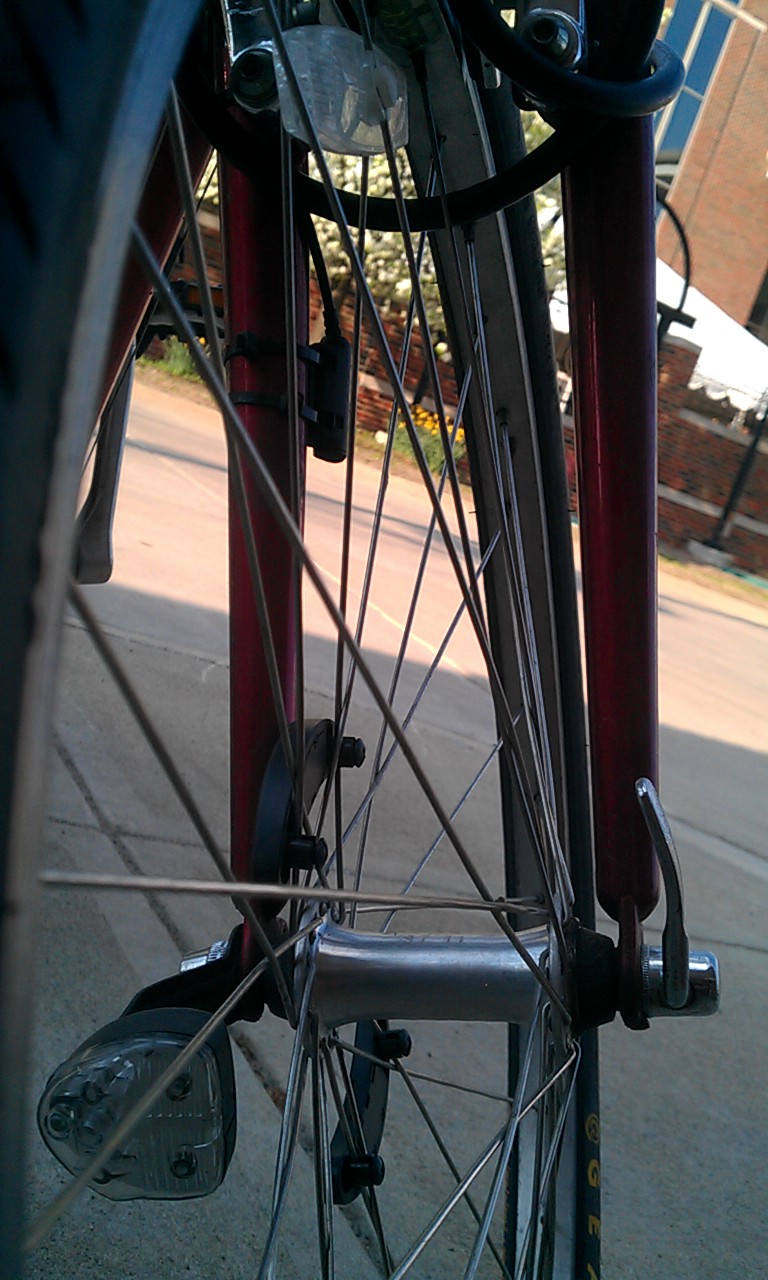 close up of my bike's front wheel while parked in the bike rack